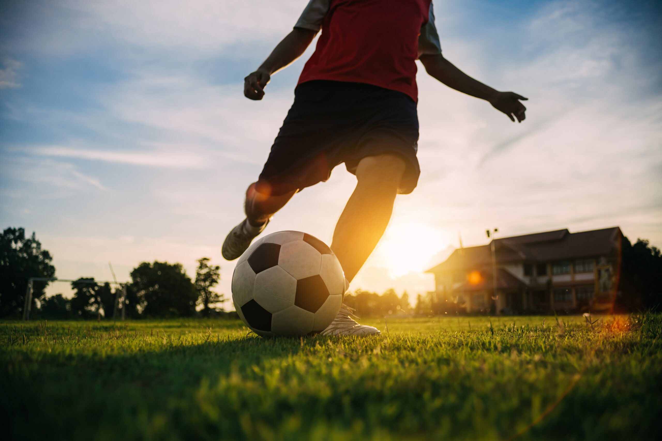 A person on a soccer field, about to kick a ball across the grass.